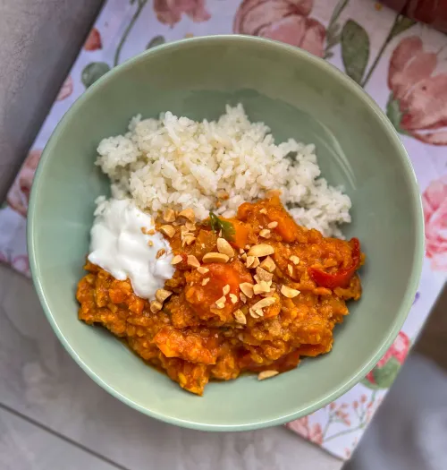 Kremasti kari sa crvenim sočivom, batatom i povrćem u dubokom tanjiru