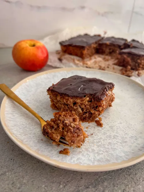 Parče sočnog kolača sa jabukama preliveno čokoladnim ganašom
